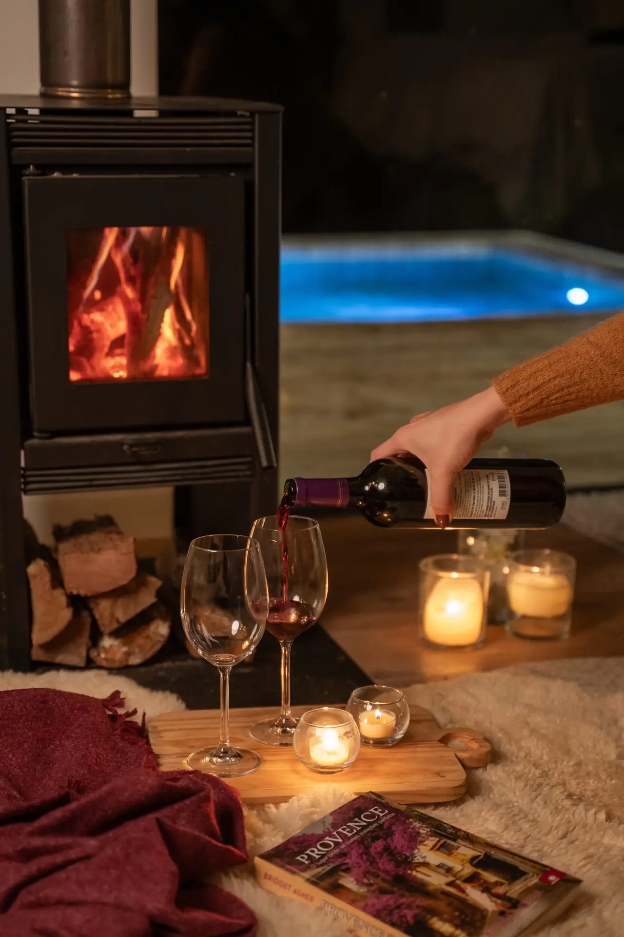 Lareira com taças de vinho e piscina aquecida iluminada à noite na Cabana La Provence, Rancho Queimado